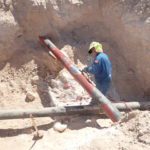 Worker repairing a pipe in a trench.