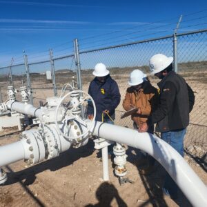 Three workers inspecting a pipeline valve.